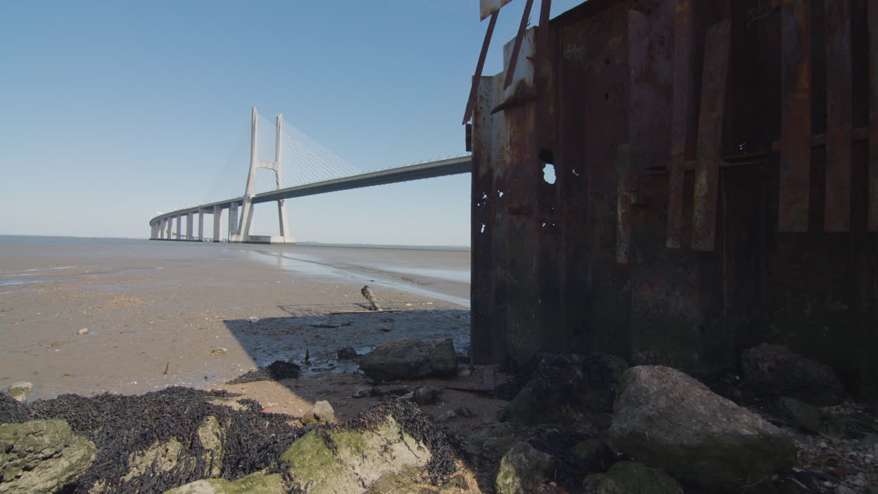 Rusty structure near a beach. Low tide river with bridge. Mankind ruins. Apocalyptic wasteland