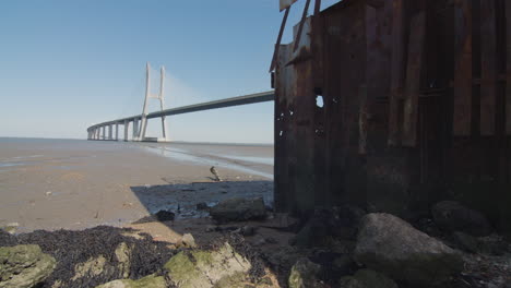 rusty structure near a beach. low tide river with bridge. mankind ruins. apocalyptic wasteland