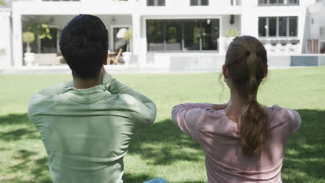 Feliz-Pareja-De-Lesbianas-Caucásicas-Practicando-Yoga-En-Un-Jardín-Soleado,-Cámara-Lenta