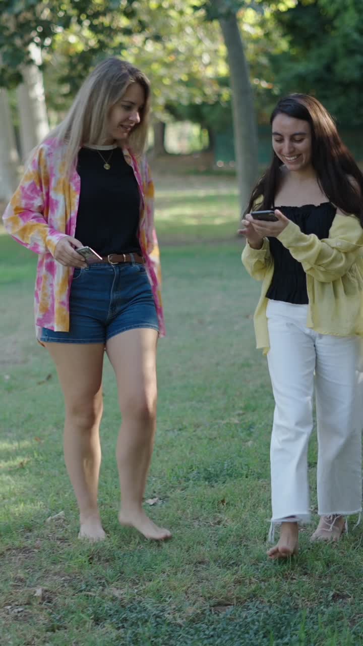 Two women walking barefoot in the park