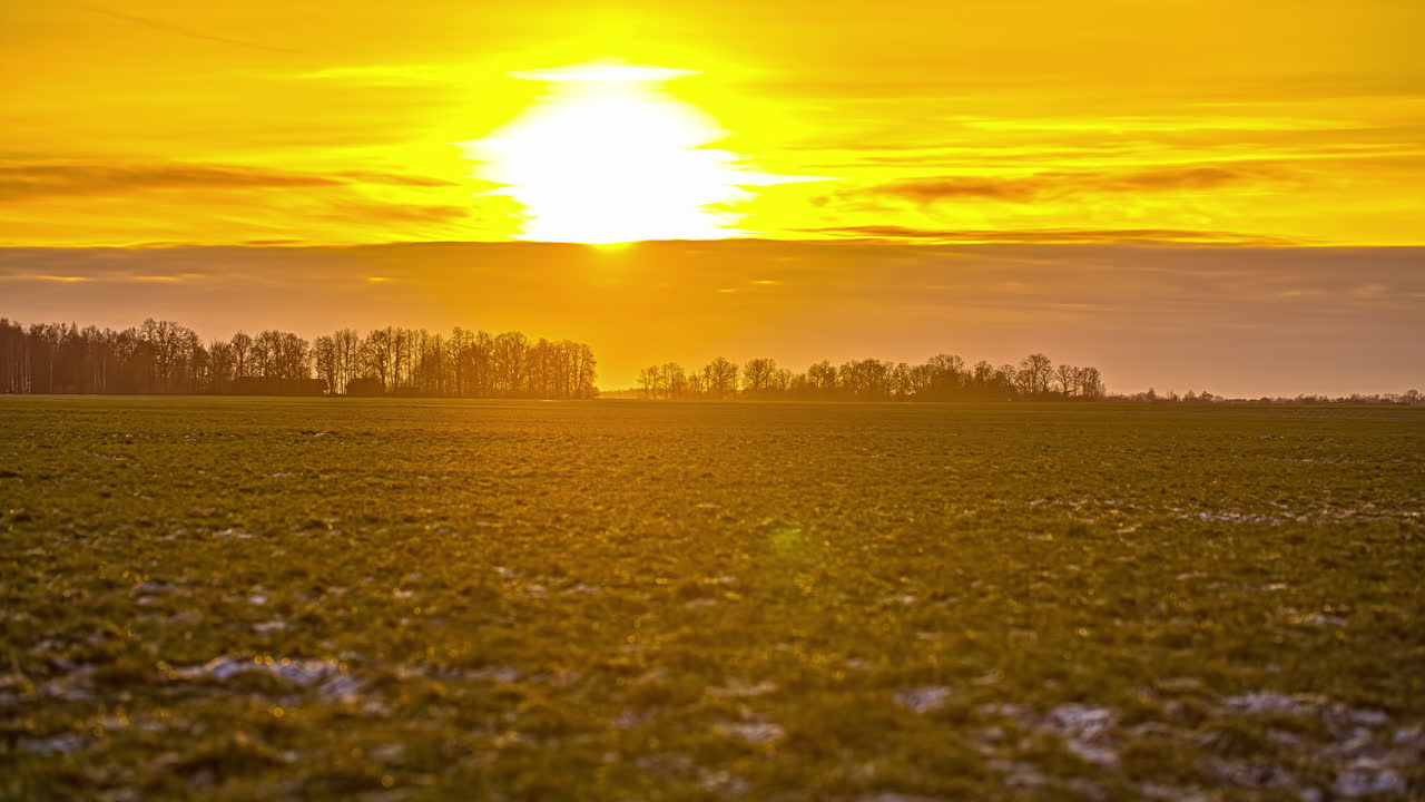vista estática de nieve blanca en praderas verdes sobre tierras de cultivo durante el invierno al atardecer en timelapse