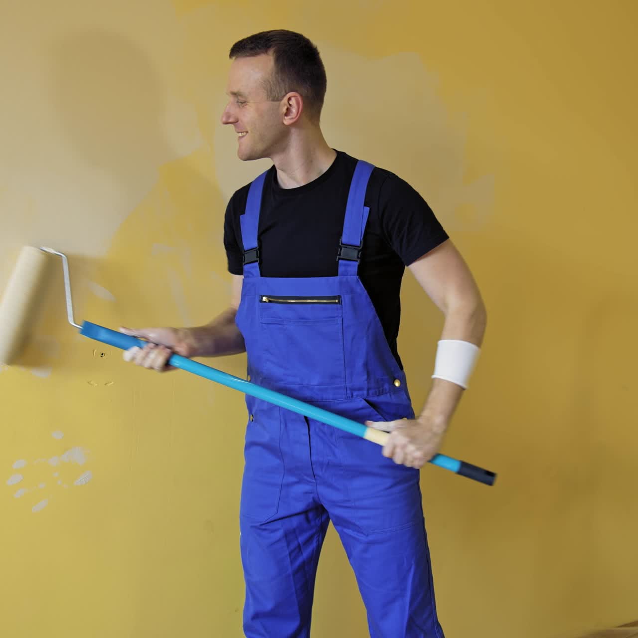 Uomo dipinge parete con rullo. Imbianchino al lavoro che dipinge la parete con il rullo.