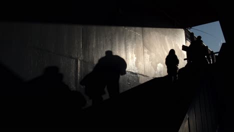 shadows and silhouettes of people at stairs of the galata bridge, istanbul, people fishing at the background