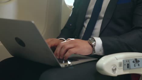 young businessman using laptop computer in airplane