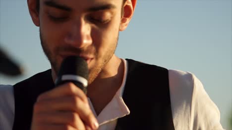 man singing with microphone outdoors