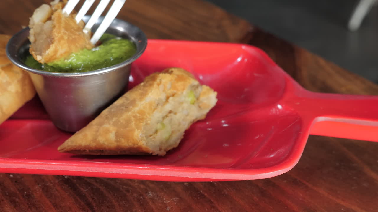 tenedor recoge samosa y se sumerge en chutney verde brillante, control deslizante de cámara lenta de cerca hd