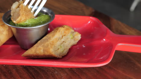 fork picks up samosa and dips into bright green chutney, slider slow motion close up hd