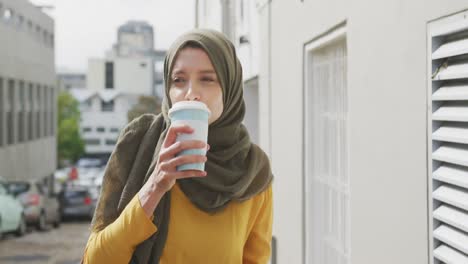 Frau-Trägt-Hijab,-Geht-Auf-Der-Straße-Und-Trinkt-Einen-Kaffee-Zum-Mitnehmen