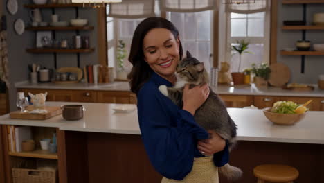 a woman holds and shows affection to her cat in a home kitchen