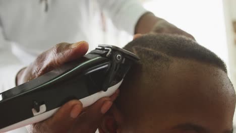 hombre africano haciendo acabados en el cabello de un niño africano