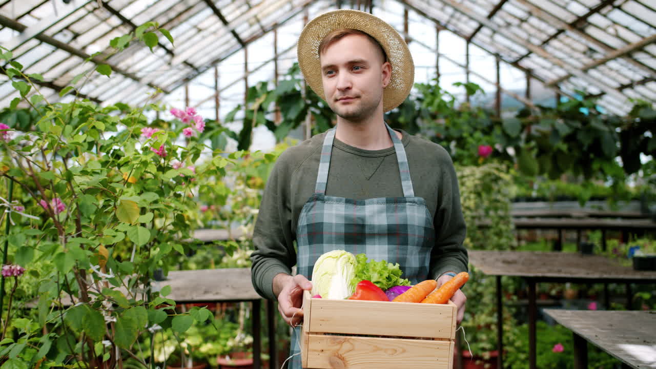 Farmer holding a wooden crate of fresh vegetables in a greenhouse