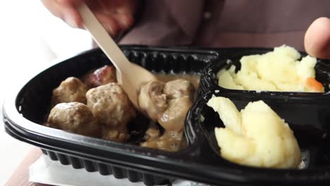persona comiendo albóndigas con puré de patatas y salsa