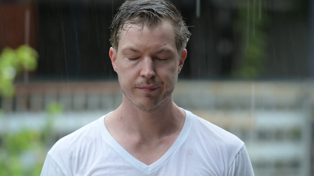 Face of sad young man alone in the rain outdoors