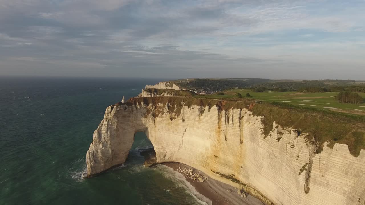 Aerial drone shot over white cliffs and three natural rock arches of Etretat.