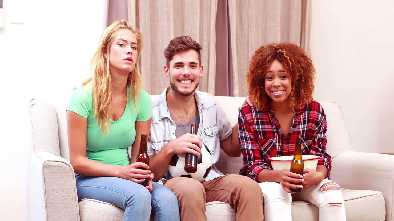 웃는 친구 들 이 팝콘 을 먹고 맥주 를 마시면서 tv 를 보고 있다
