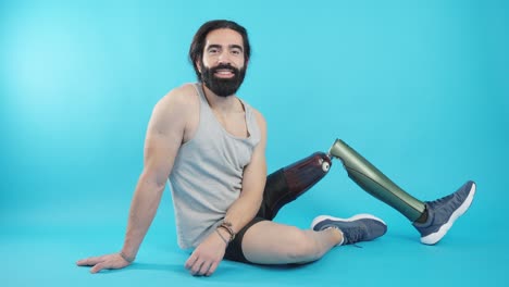 a man with a prosthetic leg smiles while sitting on a blue background