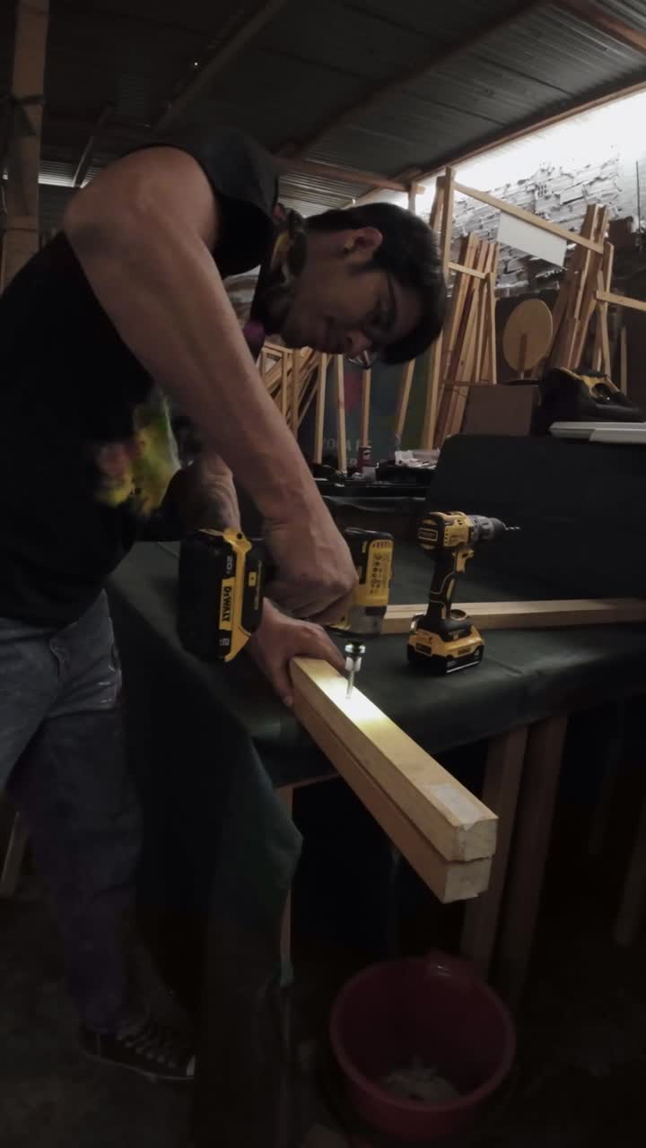 Man Drilling Screws into Wood Planks in a Workshop