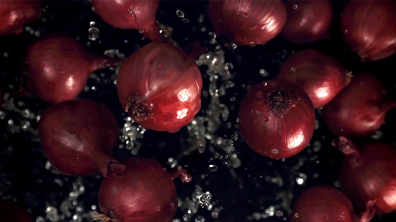 Fresh Red Onions Splashing with Water in Slow Motion