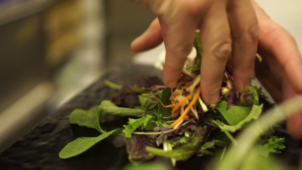 cámara lenta - preparación de ensalada verde fresca y saludable en un restaurante de lujo - primer plano
