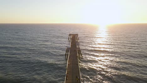 an aerial drone shot fly over the san clemente pier, california during sunset