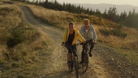 Couple-riding-sport-bikes-in-landscape.-Active-woman-and-man-cycling-on-road