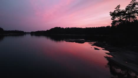 Rocas-De-Sobrevuelo-Aéreo-Hacia-La-Costa-Al-Atardecer-Rosa,-Suecia