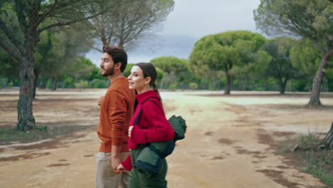 Family-enjoy-forest-stroll-holding-hands-vertical.-Happy-couple-walking-on-park.