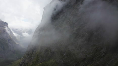 winding road passing thru the mountains, fog, and clouds in milford sound new zealand on the south island