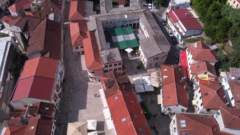 Vista-Aérea-De-Herceg-Novi,-Montenegro,-Edificios-Del-Casco-Antiguo-Y-Paisaje-Urbano-Junto-Al-Mar-Adriático,-Revelando-Un-Disparo-De-Drone