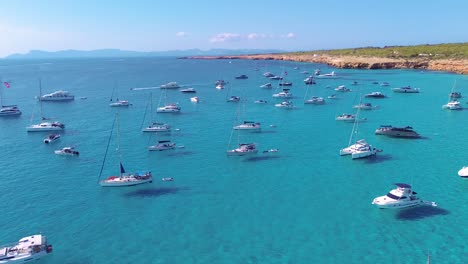 aerial drone view of group of yachts or flotilla in formentera's crystal clear cove