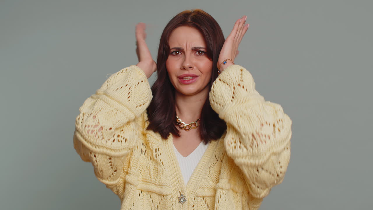 짜증나는 젊은 여성이 귀를 막고, 아무 몸짓도 하지 않고, 조언을 피하고, 시끄러운 목소리를 무시하고