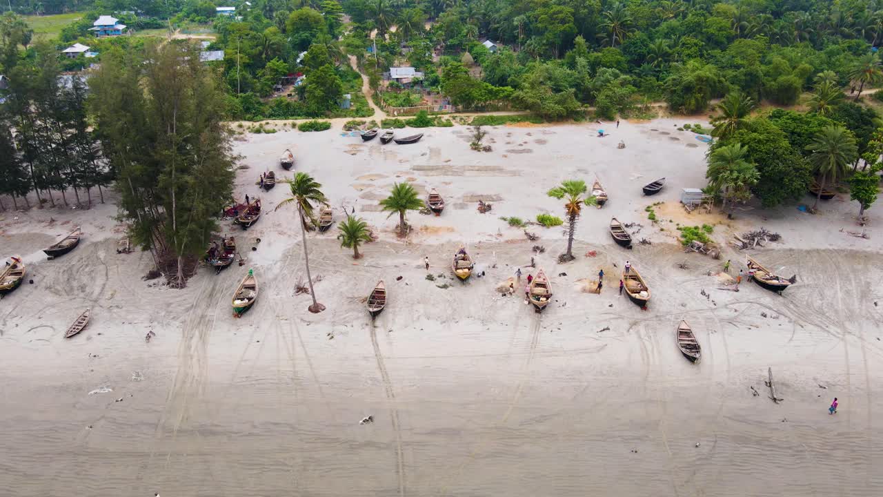 Pescatori sulla spiaggia che preparano le reti da pesca vicino alle loro barche in Bangladesh.