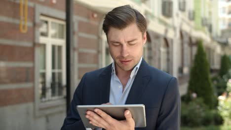 closeup businessman browsing internet outdoors. man holding touchpad at street