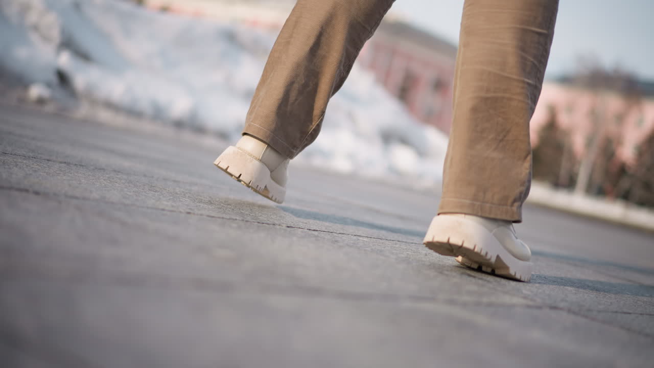 Boots scraped gently against frozen tiled plaza floor as woman spun gracefully, coat hem catching breeze like flag in slow motion under pale winter sky, creating fluid choreography joyful momentum