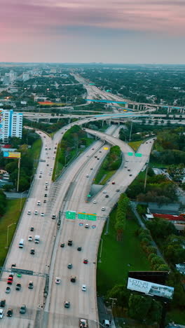 green cityscape of modern american metropolis with busy highway in the middle. aerial perspective on miami beach, florida, usa at sunset. vertical video