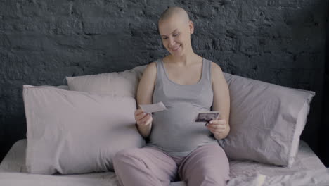 pregnant woman looking at a picture on a bed