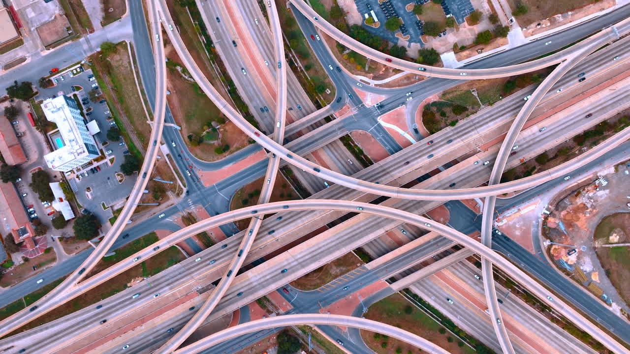 Many cars move by the stunning interchange with roads and trestles. Lively traffic in the big city. Top view