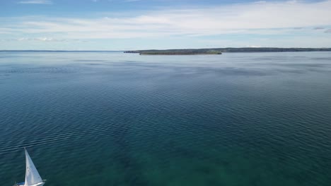 Flying-towards-Kelly's-Isand,-Conception-Bay,-Newfoundland-with-a-sailboat-in-the-foreground