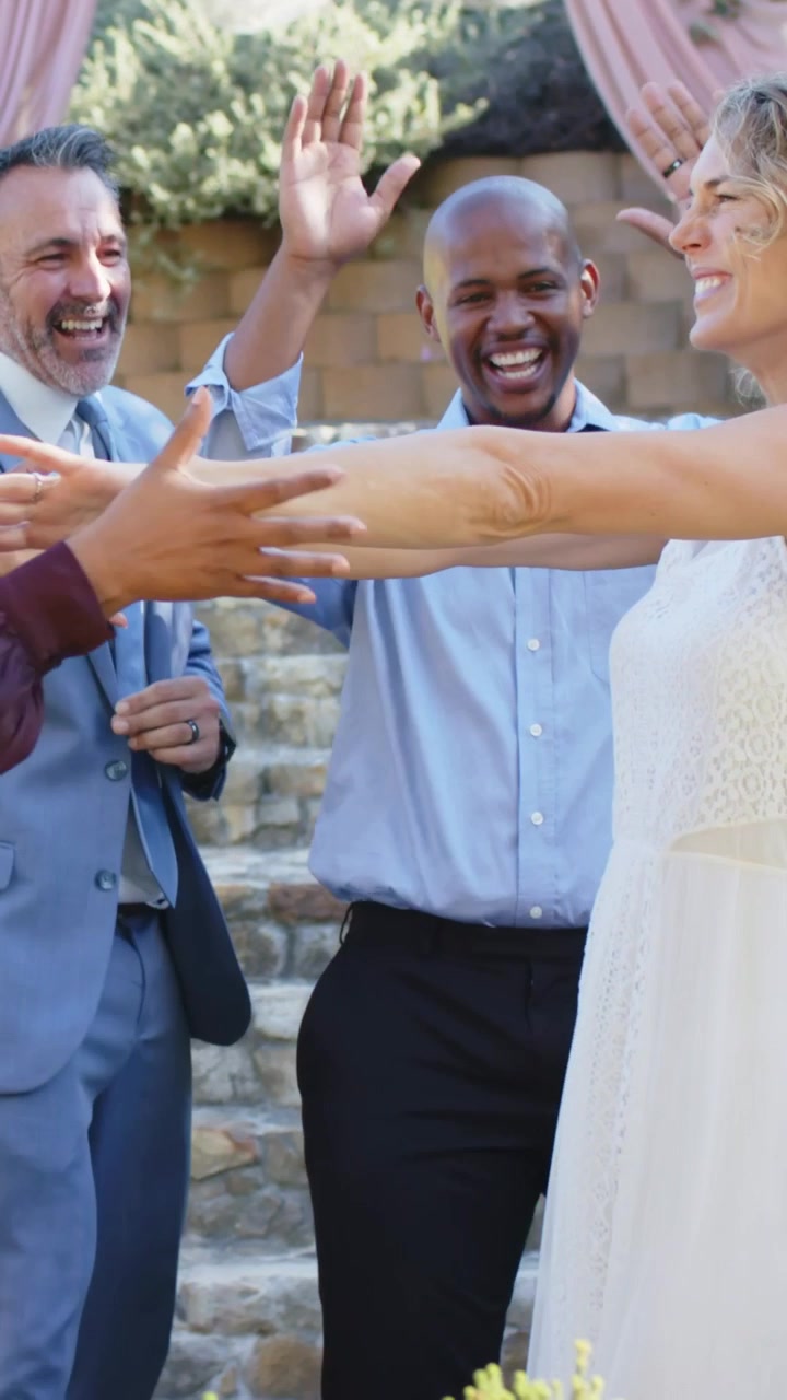 Vertical video: Raising arms woman in white dress taking left hand reaching in at steps, cheering