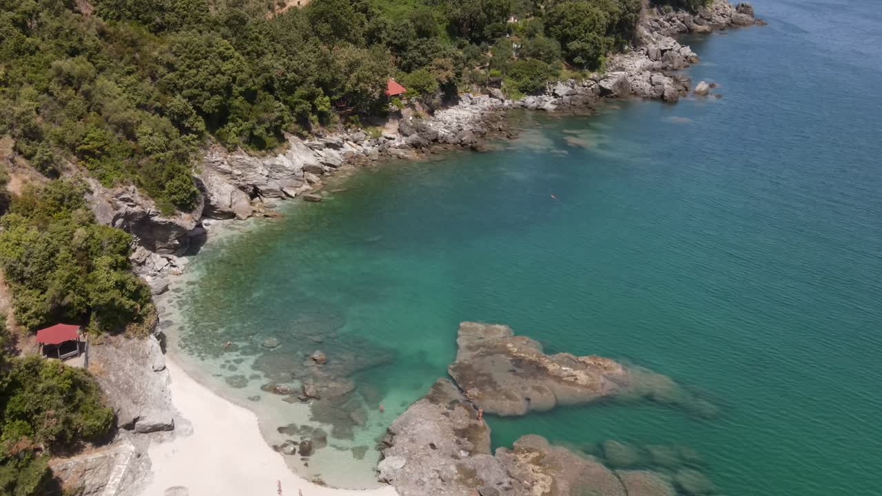 Vista aerea di una bellissima spiaggia sabbiosa con acqua cristallina, lettini prendisole e una lussureggiante vegetazione verde