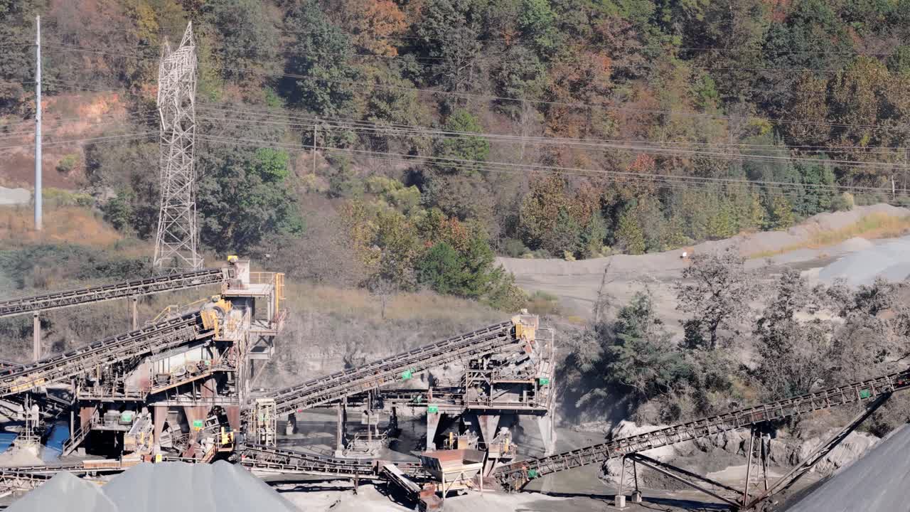 Complesso sistema di carico a nastro trasportatore e impianto di frantumazione con semirimorchio che trasporta riempimento aggregato dietro, panoramica aerea