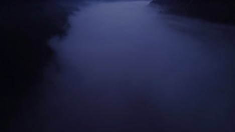 dark revealing aerial drone fly at sunset over a sea of fog in a mountain valley with orange sky