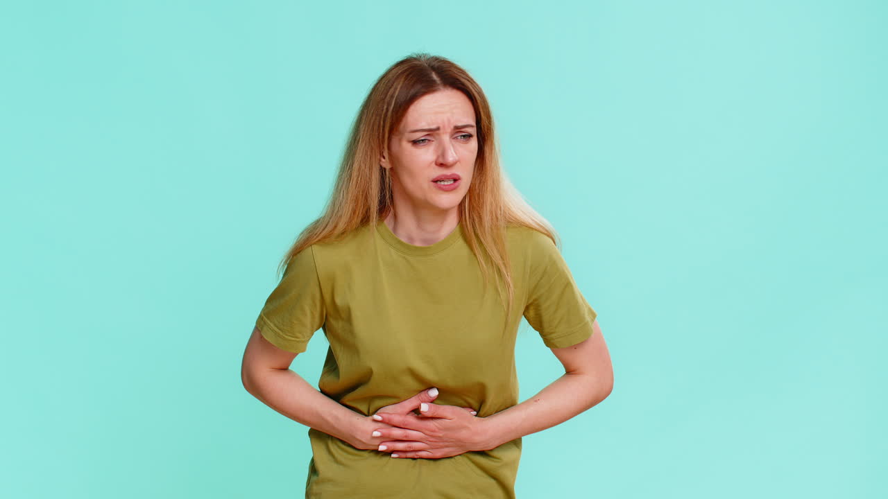 Woman touching belly with painful face expression suffering from cramps period or food poisoning