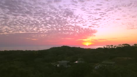 majestuosa puesta de sol rosada, volando de vuelta sobre villas en la ladera y la playa