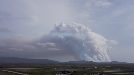 disparo de lapso de tiempo del tráfico en la carretera frente a la explosión del volcán en el fondo