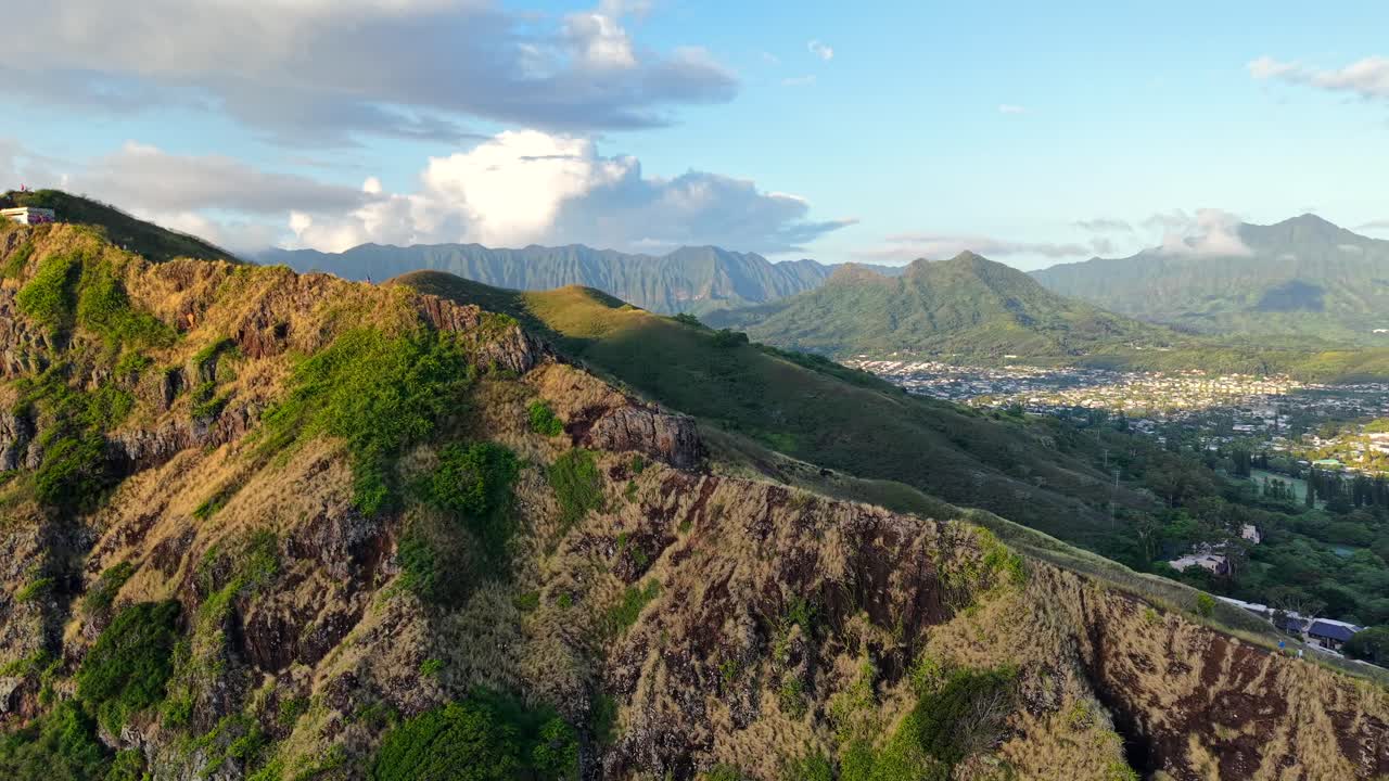 Happy hiking couple waves from a cliff on Oahu, Hawaii, aerial pull-back shot