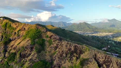 happy hiking couple waves from a cliff on oahu, hawaii, aerial pull-back shot