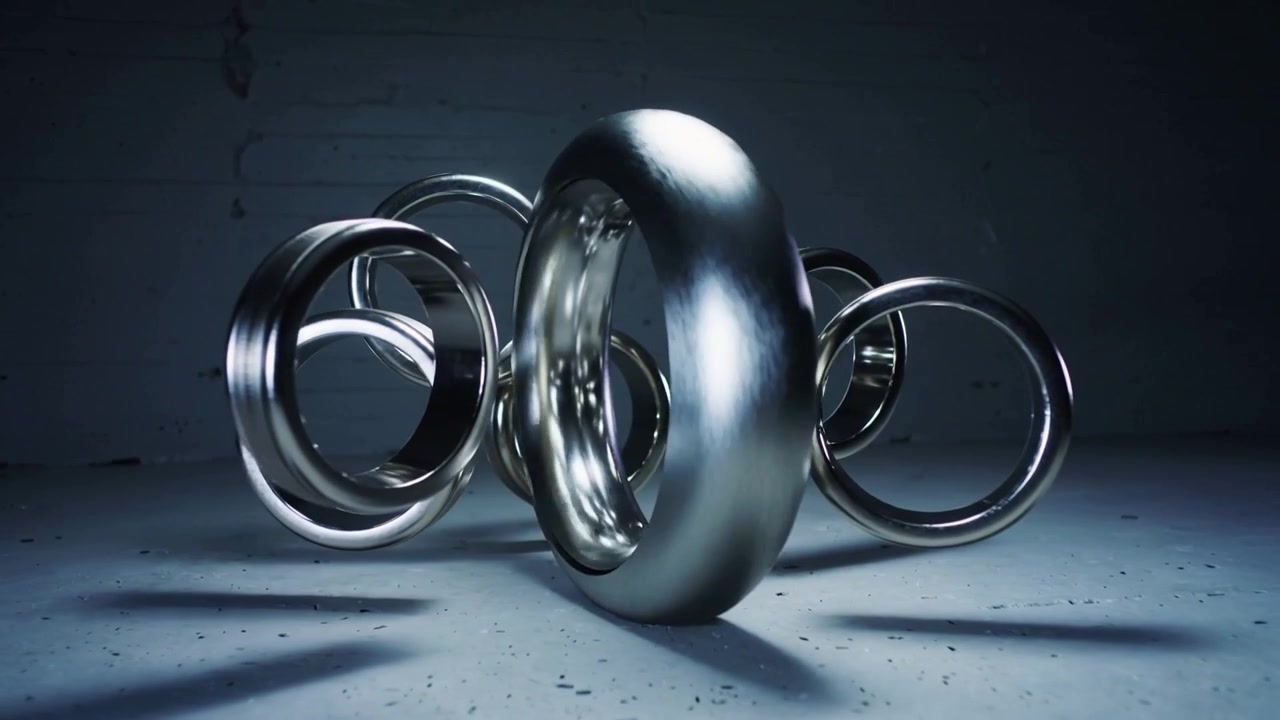 Starting torus sculpture rotating with small rings orbiting above concrete floor, showing glints