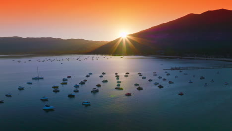 bright orange sky over the lake tahoe at sunset. numerous boats enjoying the sundown view from water. aerial view.