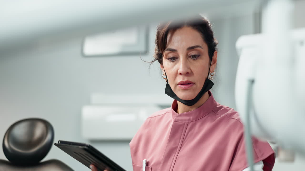 una dentista mujer usando una tableta en un consultorio dental
